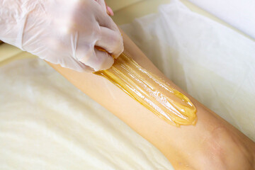 The sugaring master applies the paste to the legs.