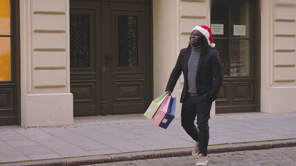 a black man with holiday bags crosses the street. High-quality photo