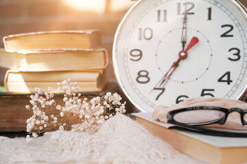 Books, glasses and alarm clock at morning with sunlight 