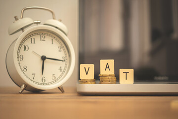VAT and coins on desk with alarm clock and laptop. Business and managament background photo