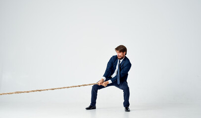 a man in a suit pulls the rope career office light background