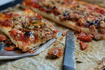 Close-up of homemade tuna pizza, sliced on an oven tray.