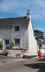 St Mawes, Cornwall, England, UK. 2021.  Holiday maker strolling past a whitewashed cottage in St...