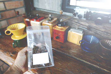 Traditional coffee drink related objects. Hand Coffee Beans at Plastic  Packaging On Table....
