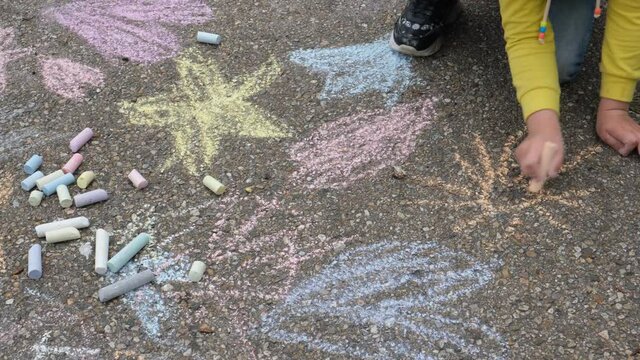 Child paints outdoors. Little girl drawing colored chalk on the asphalt . Creative development of children