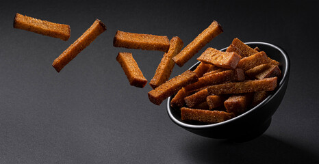 Falling rye croutons on black background 