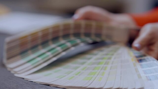 Female hands showing multicolored choice of color samples indoors. Unrecognizable Caucasian young woman advertising variety of design for furniture in household store