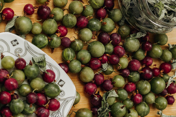 Green and red gooseberries. Gooseberries on a wooden surface and on a white plate. Plate with gooseberries