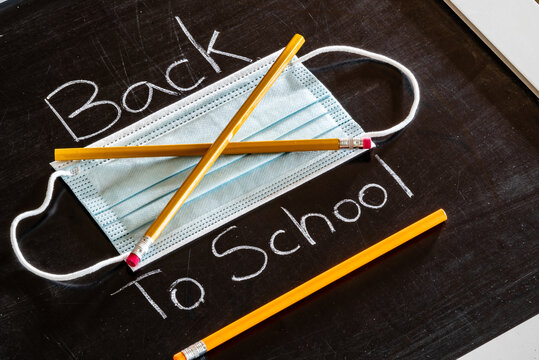 Back To School Mask Mandate Concept With Mask Crossed Out By Pencils. No Masks.