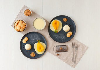 Panna cotta, traditional Italian dessert with muscat poached pears and creme Anglaise, crushed hazelnuts, caramel lentils and biscuits. Flat lay, top down view.