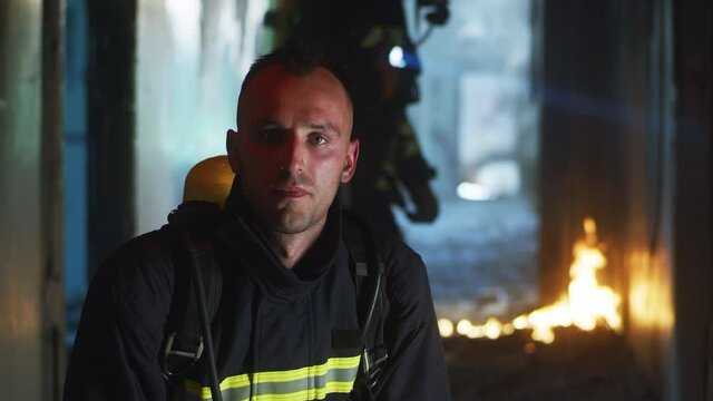 Firefighter looking at camera in burning hallway