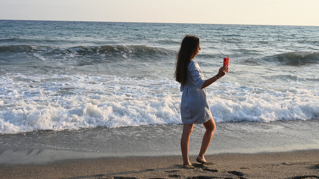 Young woman taking pictures of the sea as a keepsake 