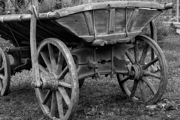 Fototapeta na wymiar Antiquarian transport. Old wooden two-wheeled cart, vehicle. Black and white photo