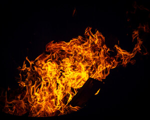a blazing fire in a fire barrel while burning wood and trash at midnight