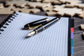 notepad with a fountain pen and puzzle pieces