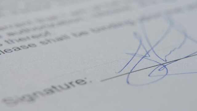 Close-up of a focused young businessman puts his signature on a paper.