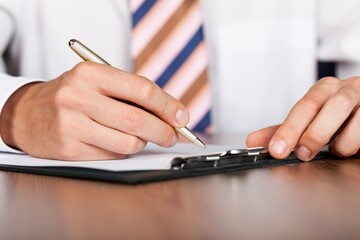 Closeup of a Businessman Writing on Clipboard