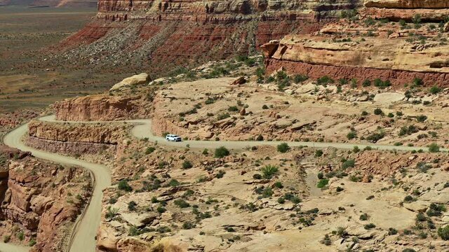 Car Driving On Dirt Road Carved Out Of Steep Rock Cliffs. Moki Dugway On State Route 261 In San Juan County, Utah. wide aerial