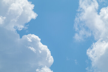 Fluffy white high clouds framing bright blue sky, cloudscape background. Skyscape natural heavenly scenery