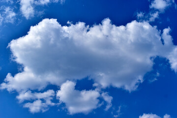 White cumulus cirrus clouds in a blue sky