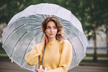 Portrait of a young beautiful model girl in the city in the rain with an umbrella