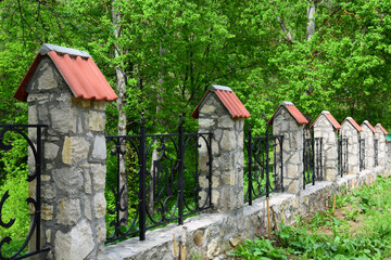Wrought iron fence with stone columns and caps of tiles