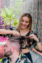 Young girl cuts hair and braids a young man with a beard