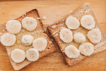 Homemade Banana Toast for summer breakfast on wooden plate.