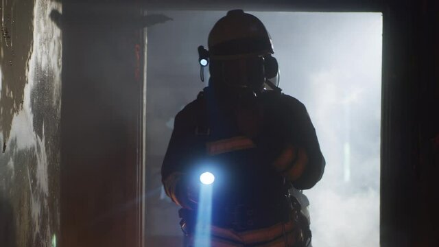 Firemen with flashlights walking through burnt corridor