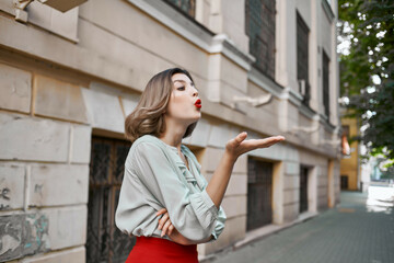 pretty woman in red skirt on the street walk near the building