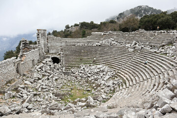 young woman tourist sits alone in the ancient amphitheatre of Termessos in Turkey