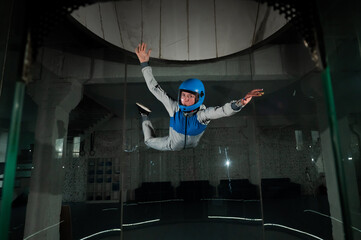 A young woman in overalls and a protective helmet enjoys flying in a wind tunnel. Free fall simulator