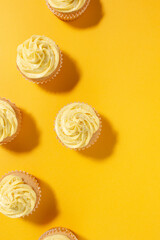 Vanilla cupcakes with yellow frosting on a bright yellow background