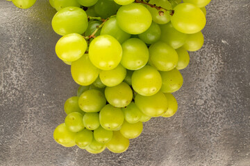 One bunch of seedless organic ripe grapes on a metal tray, close-up, top view.