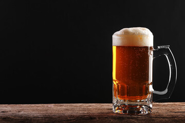 Pouring a glass of brown beer on a rough wooden table