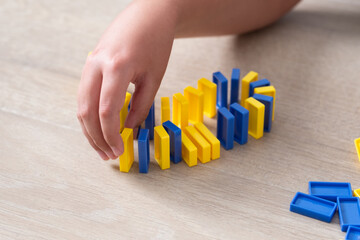 Child neatly lines up colorful domino blocks on the floor.