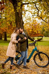 Fototapeta premium Young couple in the autumn park with electrical bicycle