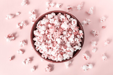 Fototapeta na wymiar Top view of a bowl of popcorn tinted in pink. Scattered popcorn around.