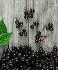 Top view of black elderberry with green leaves on a wooden desk. European black elderberry.
