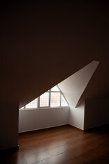 Loft, ático vacío con suelo de madera, paredes blancas y ventana triangular de vidrio. Lugar...