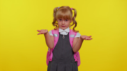 Teenage student girl dressed in school uniform raising hands in indignant expression, asking why, what reason of failure, demonstrating disbelief irritation by troubles on yellow studio background