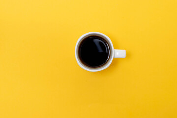 top view of white cup with coffee in isolated yellow background, hot caffeine drink