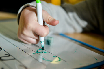 young child/person writing on a clipboard, learning how to form letters. 