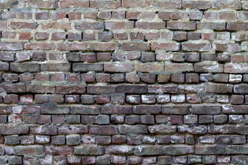 An old brick wall weathered with missing cement joints