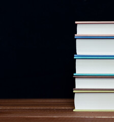 Books stacked on table. A simple composition of many hardback books  on a wooden table Back to school. Education.