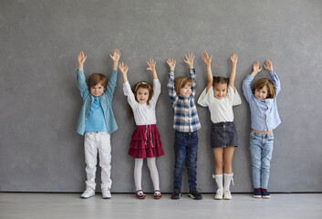 Studio portrait of happy preschool children. Group of several cute little Caucasian kids raising...