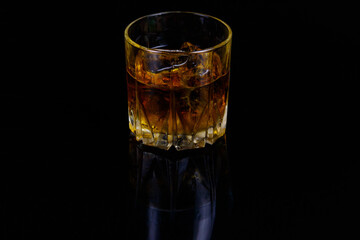 Glass of whiskey with ice on a black background