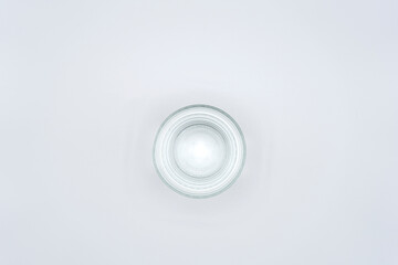 Vaso transparente con agua, vista cenital, fondo blanco.