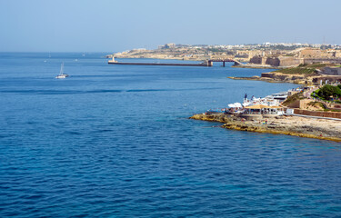 Fototapeta premium Sliema rocky coastline, Malta, with cafes, bridge and lighthouse.