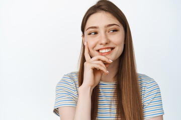 Happy people. Close up of young woman smiling aside, looking thoughtful at copy space, standing over white background